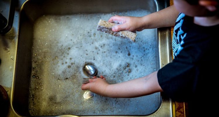 Anak mencuci piring sendiri secara mandiri.